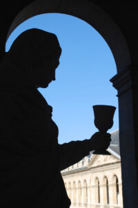 Photograph by Claudia Meyer of the silhouette of a statue against an ancient building.